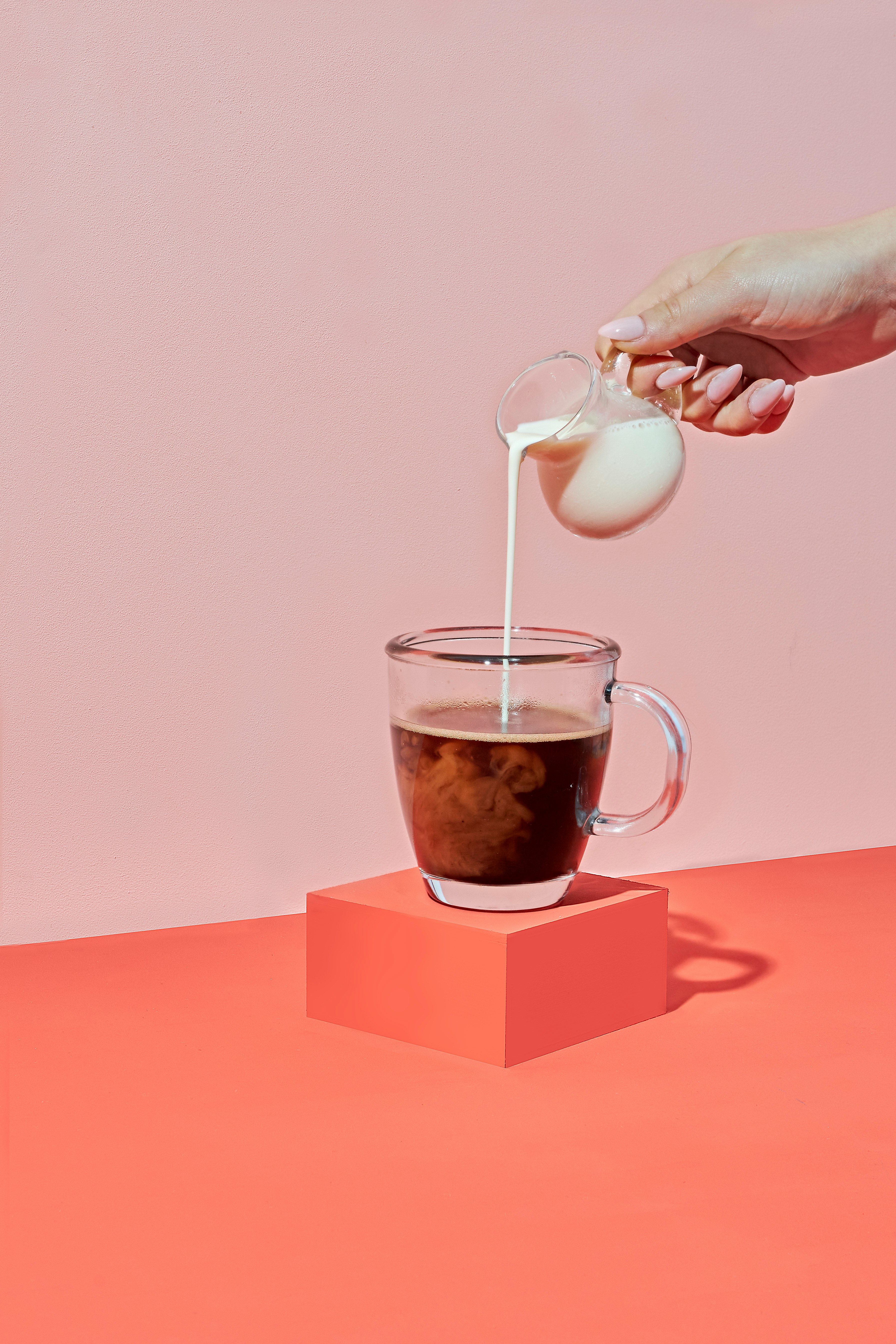 person pouring milk on clear glass mug